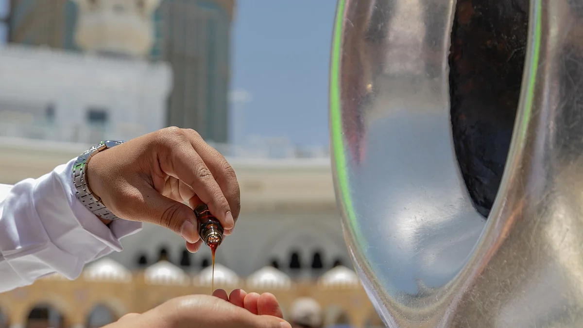 A hand perfuming the silver frame of the Black Stone on the corner of the Kaaba