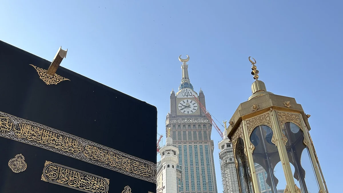 A corner of the Kaaba beside the golden enclosure of Maqam Ibrahim, with the Makkah Clock Tower behind