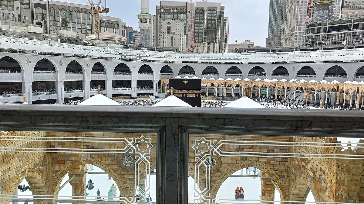 The Kaaba and the mataf seen through the railings of an upper floor of Masjid al-Haram
